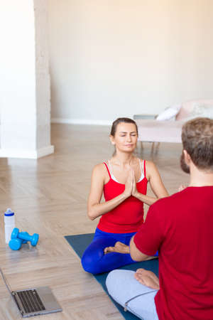 Couple meditating at home with online yoga tutorial. Vertical photo.