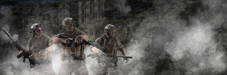 Three mercenary soldiers during a special operation in the smoke against the background of a ruins -...