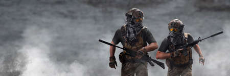 Two military mercenaries march against the background of a concrete wall and smoke. Collage - one...