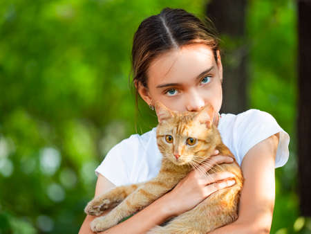 The girl is holding a ginger homeless cat in her arms.の写真素材