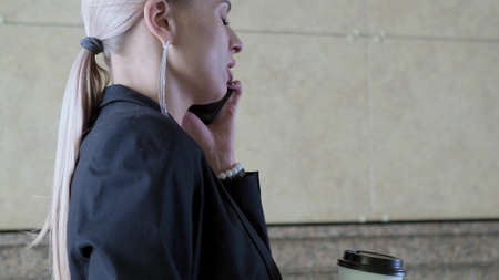 Close-up video of a businesswoman walk and talking mobile phone.