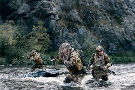 Three mercenary soldiers fording a river during a special operation.