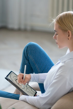 Vertical photo of a young woman draws a beautiful image on the digital pad screen.の写真素材