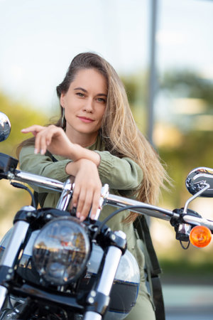 Beautiful Caucasian biker-woman posing on her bike after driving and looking at camera. Femininity...