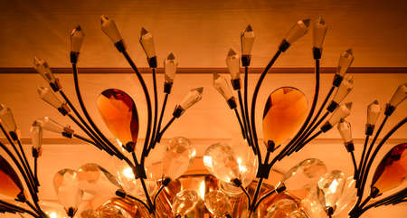 classic chandelier from glass hanging on the wooden ceiling