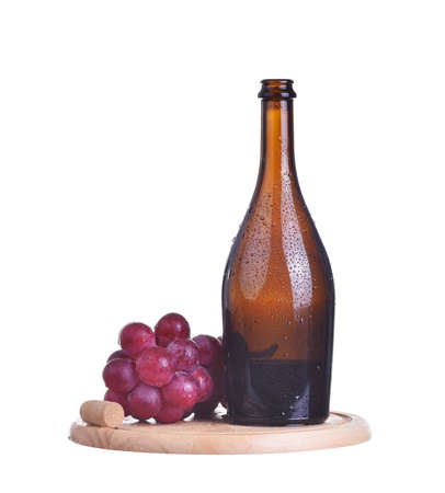 Bottle of red wine and grapes on wooden plate isolated on whiteの写真素材