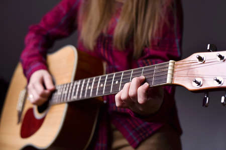 woman's hands playing acoustic guitar, close up. Playing acoustic guitar girl or woman with long hair by fingers. finger position on the chord. selective focus imageの写真素材