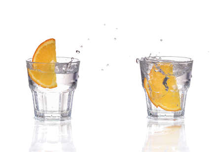 Orange or lemon slice fall in glass with water and make splashの写真素材