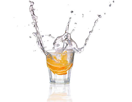 Orange or lemon slice fall in glass with water and make splashの写真素材