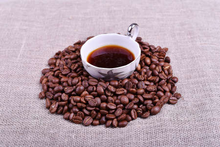 Cup of coffee with coffee beans on linen texture tableの写真素材