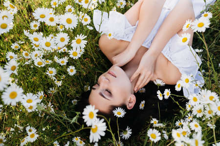 Beautiful woman lying down in daisy fieldの写真素材