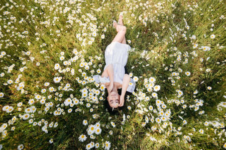 Beautiful woman lying down in daisy fieldの写真素材
