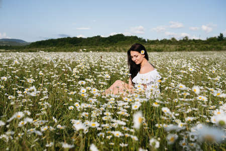 Photo of pretty brunette woman in chamomile fieldの写真素材