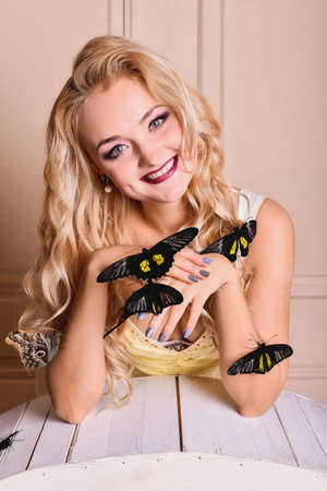 Attractive blonde girl with exotic tropical butterflies in studioの写真素材