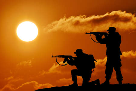 Silhouette of team soldier or officer with weapons at sunsetの写真素材