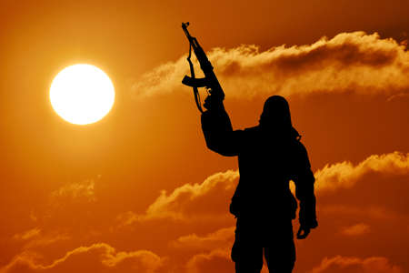 Silhouette of military soldier or officer with weapons at sunset. shot, holding gun, colorful sky,...