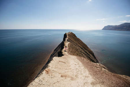 Girl in pink skirt walking at cape near sea in sunny weatherの写真素材