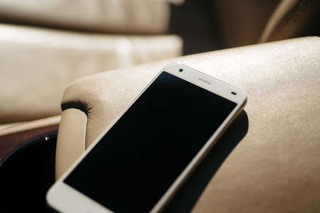 white smartphone, phone at leather armrest of carの写真素材