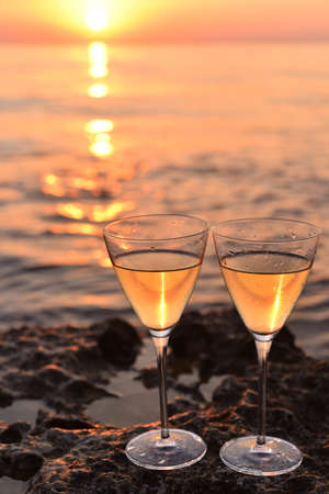 Pair of glasses with wnite wine near the sea at sunset.の写真素材