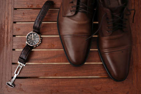 Expensive man wrist metal watch with leather strap and shoes on backgroundの写真素材