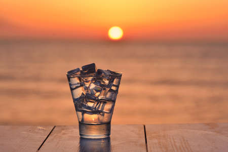 Cocktail with ice at sunset. Sea and sunの写真素材