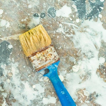 an old paint brush on an old wooden table stained with various paints. flat lay and copy space.の写真素材