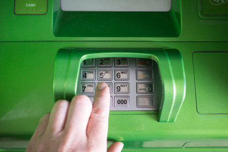 man's hand presses the buttons on the PIN keyboard of the ATM. close up.の写真素材