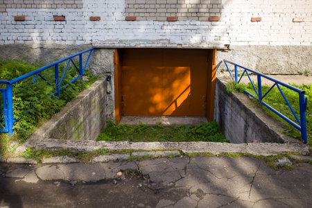 metal brown gate to the basement of a brick house