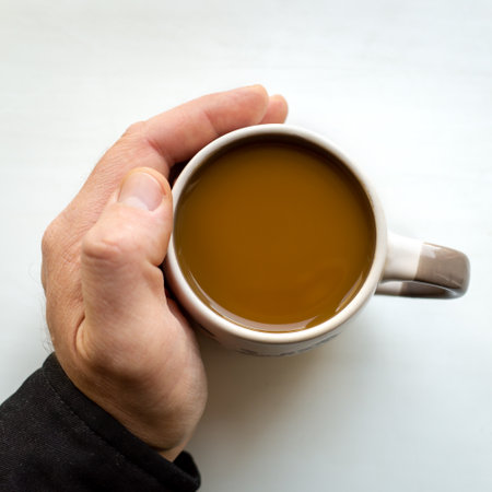 a mans hand holds a coffee mug on a white background