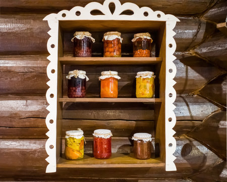 Canned compotes in large glass jars. on a wooden shelf against a log wallの写真素材