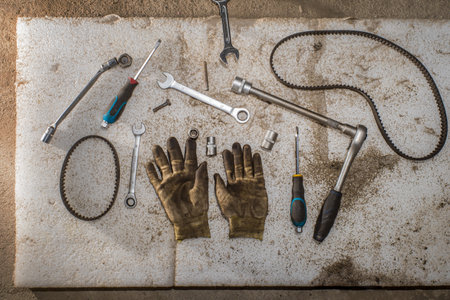 oiled gloves and tools for repairing cars with drive belts on a white polyurethane mat in the garage. flat lay and copy space.の写真素材