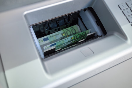 euro banknotes are in the delivery tray at the ATM. natural light