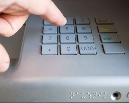 mans hand presses the buttons on the PIN keyboard of the ATMの写真素材