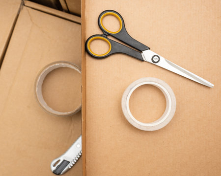 boxes for moving and delivery as well as scotch tape and an office knife with scissors. flat lay and copy space.の写真素材