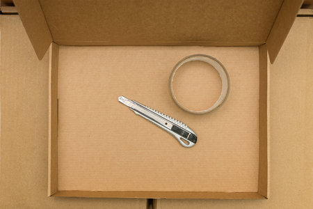 moving and delivery boxes as well as scotch tape and an office knife. top view and copy space.