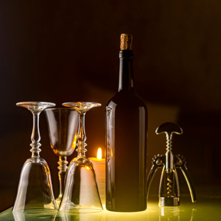 an open bottle of wine and empty clean glasses on a frosted glass table with a candle in a subdued atmosphere. close up.の写真素材