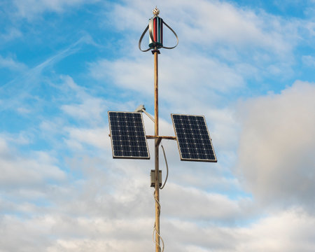 solar panels and a windscrew on a metal pole are the concept of alternative electricity. background blue sky with clouds. copyspace.の写真素材