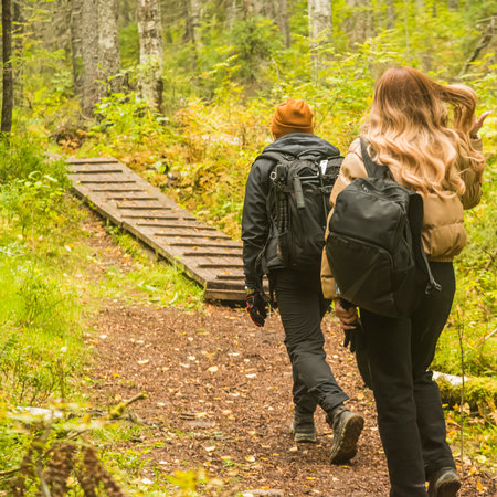 woman and a man walk along a path in a wild forest on a cloudy rainy day, the concept of travel and tourismの写真素材