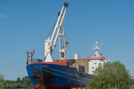 a marine vessel carries out loading at the pier. against the blue sky. sunny summer day