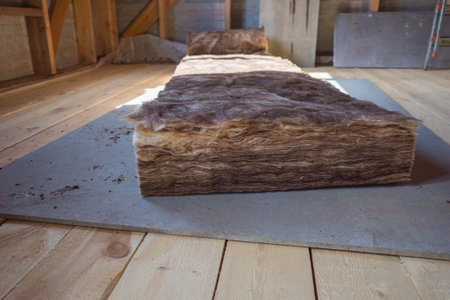 cutting insulation for laying in a frame house under construction. natural light