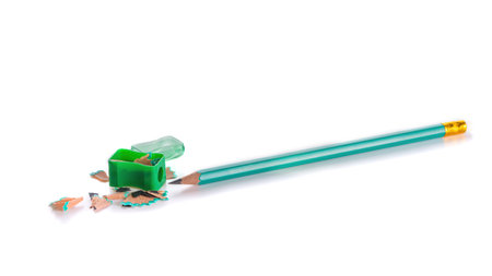 sharpened graphite pencil and pencil sharpener with pencil shavings. isolated on white. close-upの写真素材