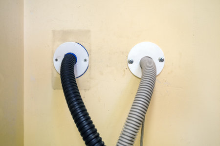 two plastic corrugated pipes for insulation of electrical wires extending into the wall
