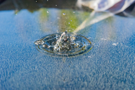 a drop falling into the water in a container against the background of greenery and nature at sunset in the evening. natural lightの写真素材