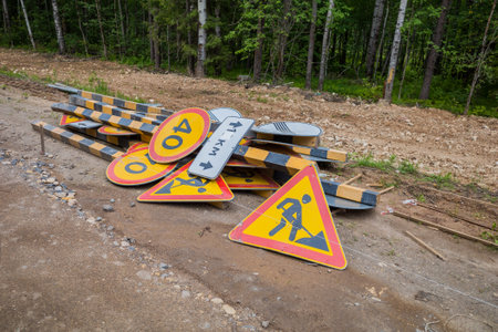 road signs warning of road works lie on the side of a dirt country road. natural lightの写真素材