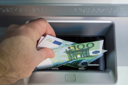 a mans hand puts euro bills in the ATM tray to be credited to the account. mortgage repayment conceptの写真素材