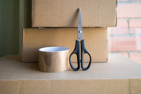 Cardboard box with duct tape and scissors on a window and room background, Online sales and packing...