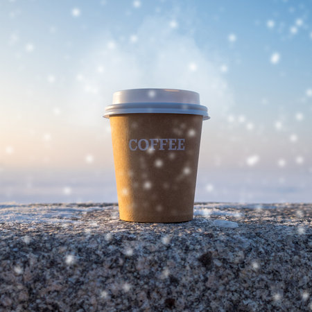 a hot cardboard cup with the inscription coffee on a granite stone against the background of falling snow and blue winter skyの写真素材