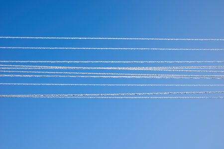 high-voltage electrical wires in frost on a blue sky backgroundの写真素材