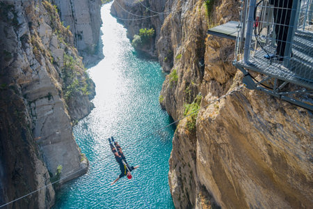 jumper flying down on a bungee jump with arms out to the sides against the background of the river and cliffs natural lightの写真素材