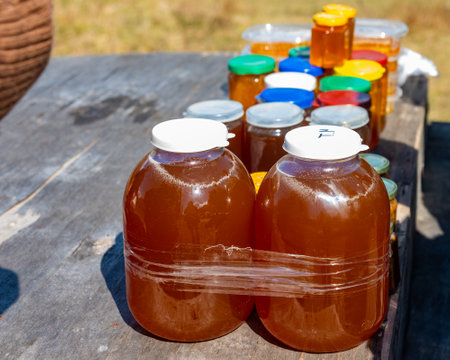 glass three-liter jars of healthy natural honey on a wooden table for sale for tourists and visitors. close-upの写真素材